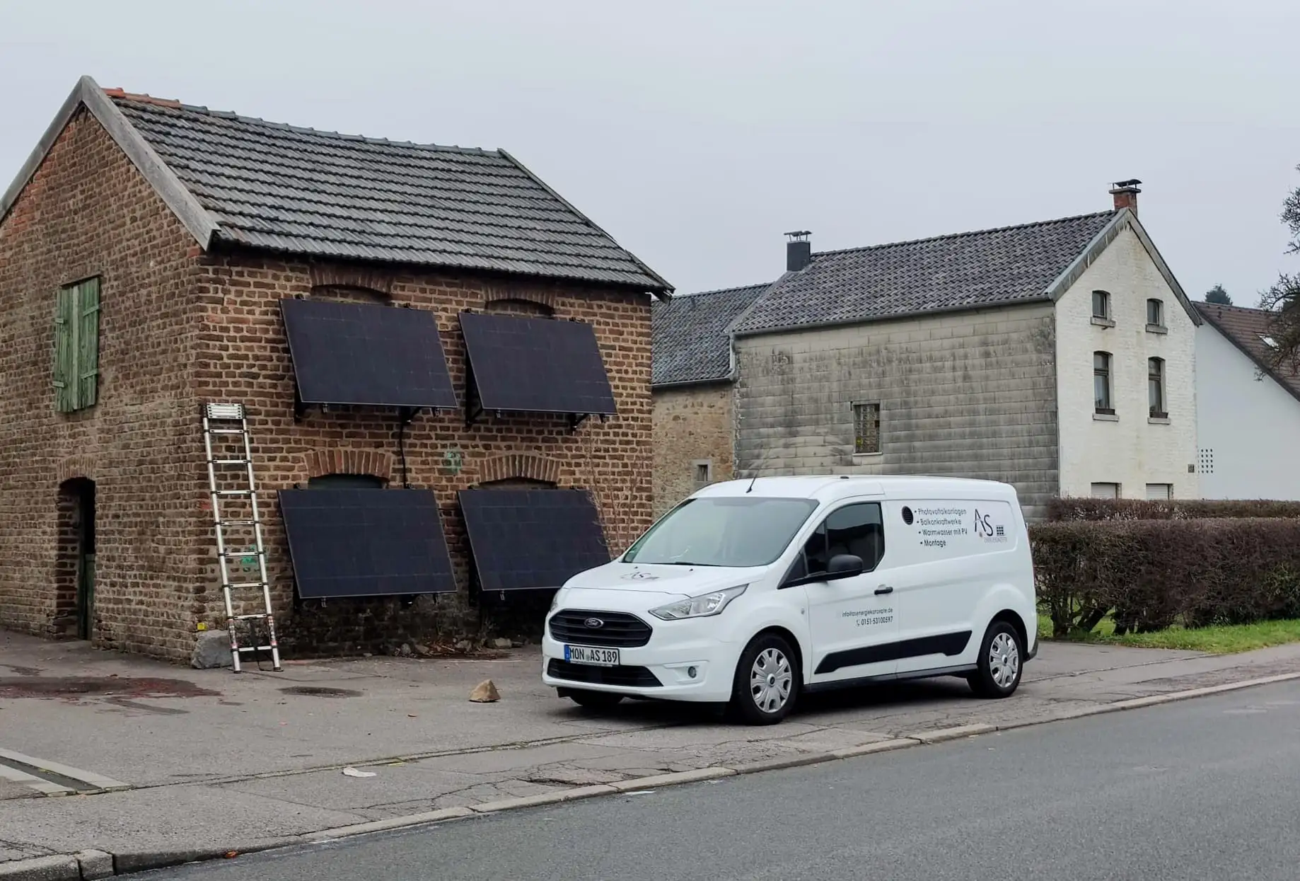 AS-Energiekonzepte Servicefahrzeug vor einem Gebäude mit Solarmodulen